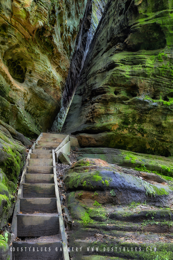 A set of wooden stairs leading the hiker to a rock crevasse passageway.